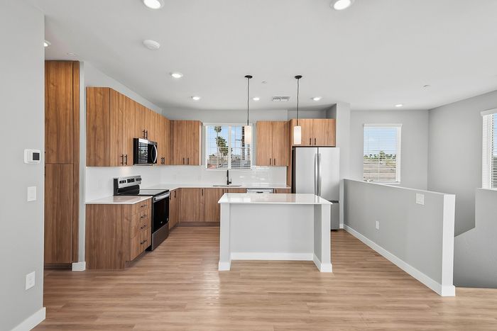 Modern open-concept kitchen with sleek wooden cabinetry, stainless steel appliances, and a spacious island.