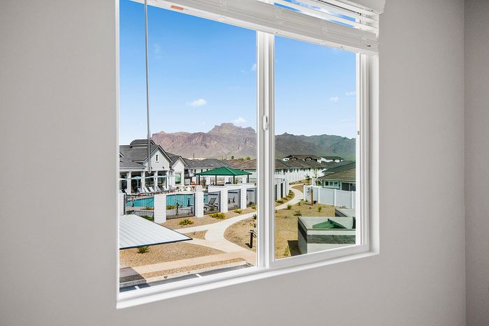 Breathtaking mountain views from the window of a modern apartment overlooking a luxurious pool and stylish community architecture.