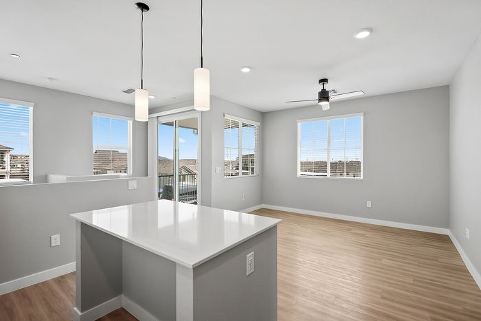 Bright and modern open-concept living space featuring elegant wooden flooring, stylish pendant lighting, and large windows for natural light.