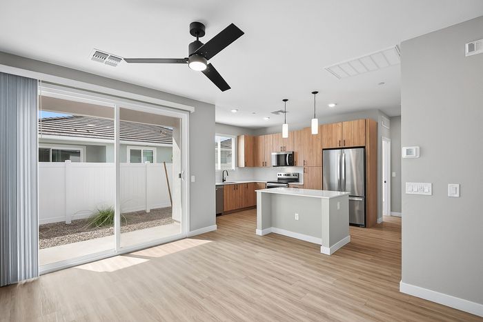 Modern open-concept kitchen with sleek wooden cabinets, stainless steel appliances, and sliding glass doors leading to a private outdoor space.