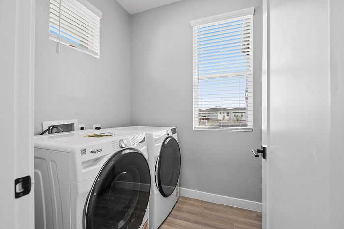 Bright and functional laundry room with sleek modern washing and drying machines, accented by natural light from a large window.