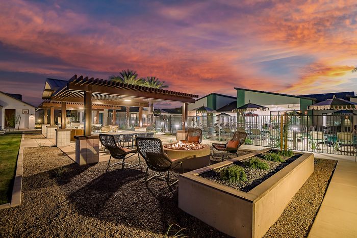 Inviting outdoor lounge with stylish fire pit and pergola, set against a stunning sunset backdrop for perfect relaxation.