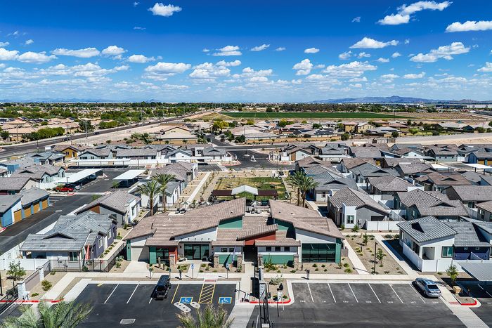 Expansive aerial view of a modern suburban neighborhood with stylish homes, manicured landscapes, and clear blue skies.
