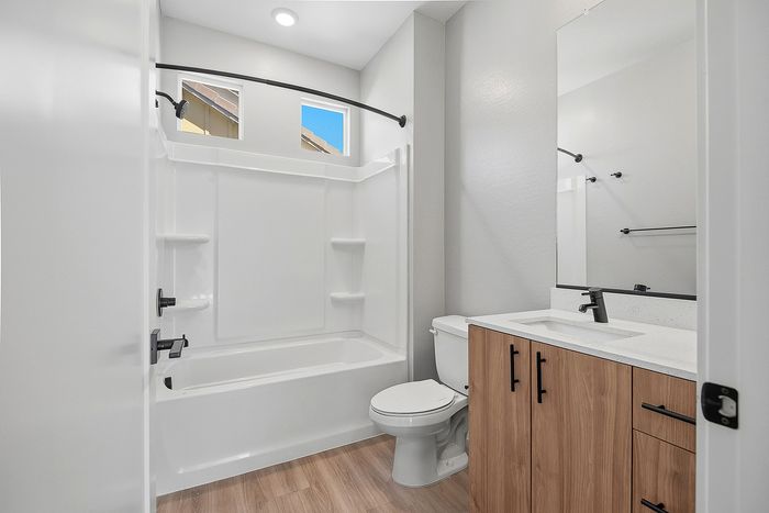 Modern bathroom featuring a sleek white bathtub, stylish wood cabinetry, and elegant matte black fixtures.