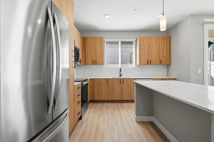 Modern kitchen with sleek stainless steel appliances, elegant light wood cabinetry, and a spacious white countertop island.