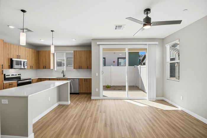 Modern open-concept kitchen and living space featuring sleek cabinetry, stylish countertops, and abundant natural light through large sliding doors.