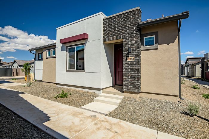Modern and stylish single-story home with a unique facade, set against a clear blue sky, showcasing contemporary architecture and low-maintenance landscaping.