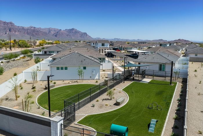 Modern residential neighborhood with stunning mountain backdrop, featuring well-maintained homes and a private fenced green space.