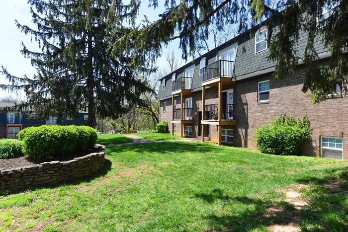 Charming apartment building with spacious balconies, surrounded by lush greenery and mature trees, offering tranquil outdoor space.