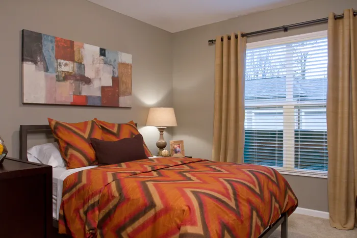 Cozy bedroom with vibrant patterned bedding, warm lighting, and modern abstract artwork.