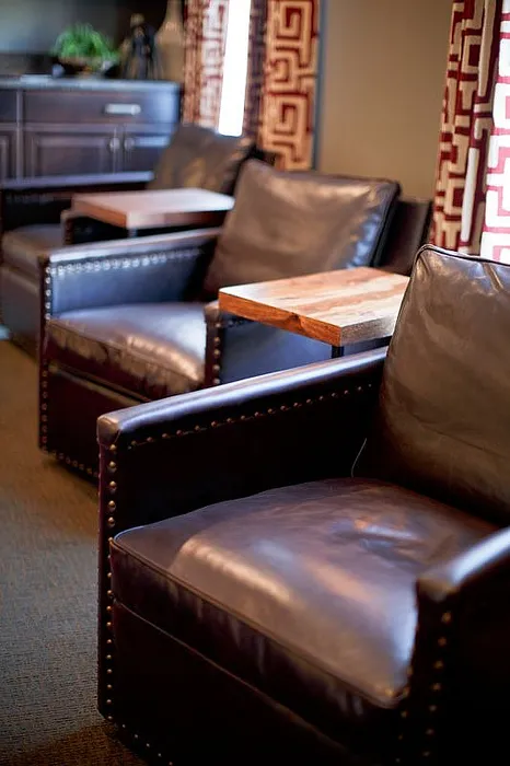 Elegant lounge setting featuring plush leather chairs with studded detailing and stylish side tables, creating a warm and inviting atmosphere.