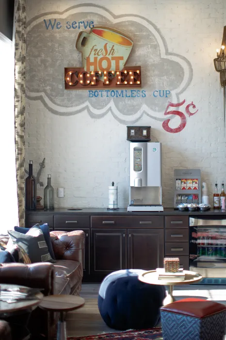 Charming coffee lounge with vintage wall art, offering a cozy seating area and a modern coffee machine for endless enjoyment.