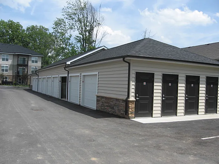 Modern storage units with sleek black doors and ample space in a well-maintained complex, surrounded by lush greenery.