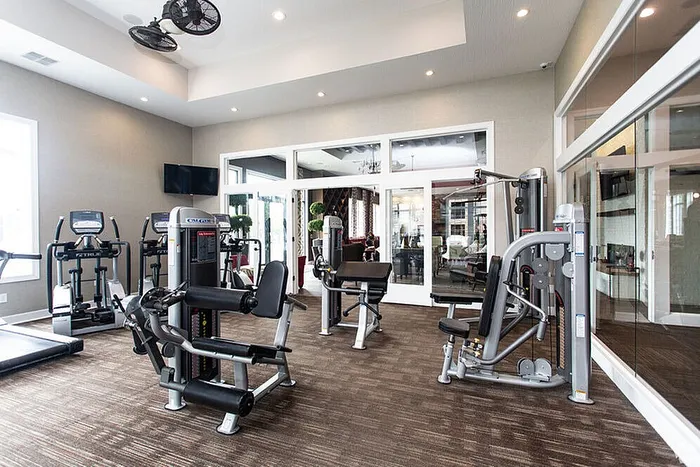 Modern fitness center with state-of-the-art exercise equipment, featuring cardio machines and strength training stations, in a bright and spacious setting.