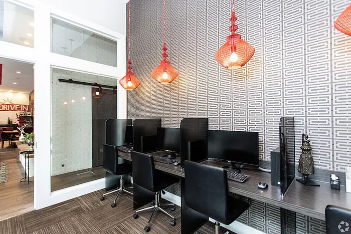 Modern co-working space with sleek workstations, vibrant red pendant lighting, and stylish geometric wallpaper.
