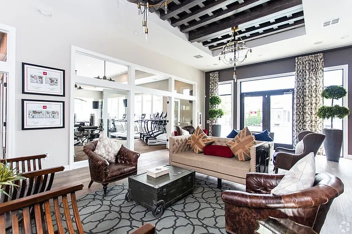 Luxurious apartment lounge with elegant furniture, contemporary decor, and chic lighting, adjacent to a modern fitness center.