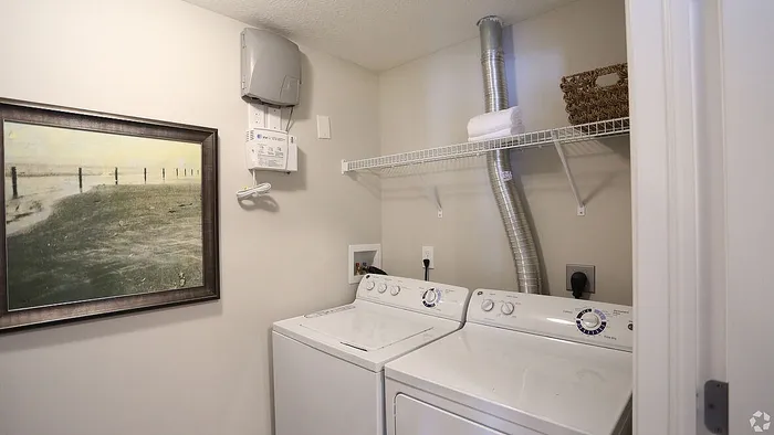 Modern laundry room with sleek washer and dryer, wall-mounted utility controls, and stylish artwork creating a clean, efficient space.