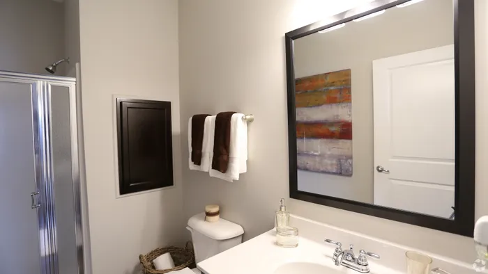 Modern bathroom featuring sleek fixtures, elegant mirror, and stylish art piece, exuding comfort and sophistication.