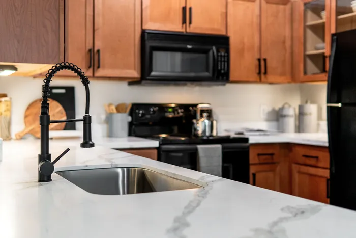 Modern kitchen with sleek marble countertops, stainless steel sink, and elegant wooden cabinetry.