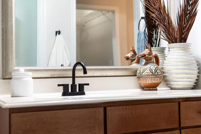 Elegant bathroom vanity with sleek black faucet, decorative pottery, and modern accessories reflecting sophistication.
