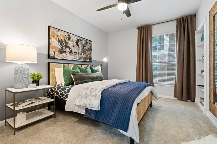 Inviting bedroom with elegant decor, featuring a cozy bed with plush pillows, stylish bedside table, and natural light streaming through large window.