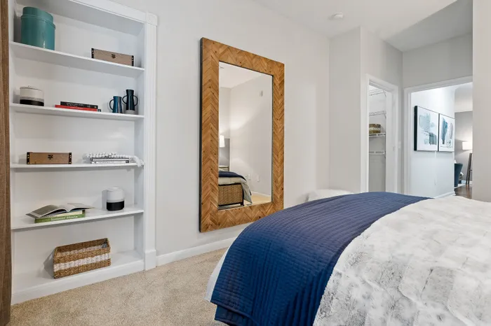 Inviting bedroom with elegant shelving, a chic wooden mirror, and plush bedding, ideal for cozy living.