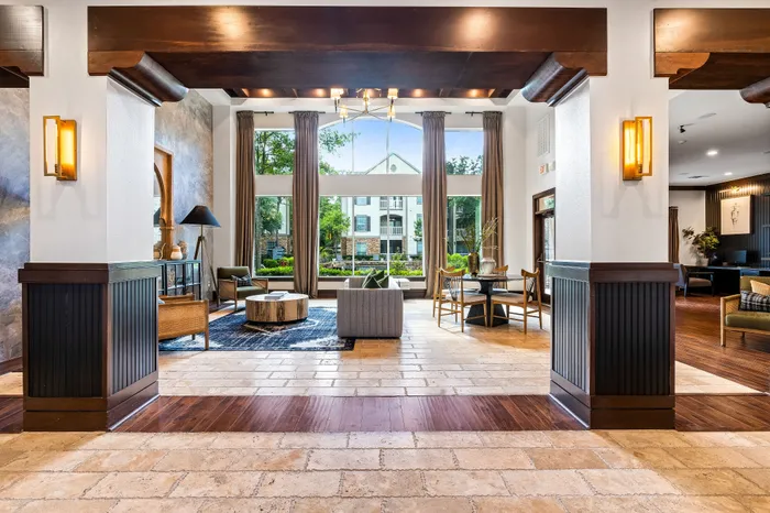 Luxurious apartment lobby with modern decor, large windows, natural light, and stylish seating areas offering a welcoming atmosphere.