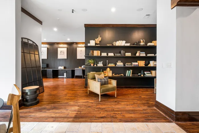 Chic, modern apartment living area with dark wood floors, stylish shelving, and cozy seating.