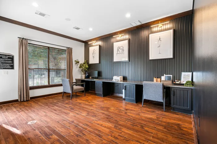 Sophisticated home office with elegant wood flooring, stylish artwork, and a sleek work desk in a well-lit room.