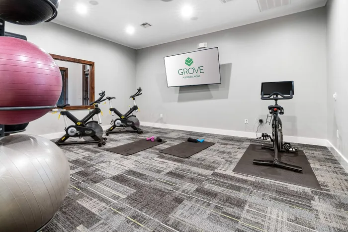 Modern fitness room with stationary bikes, exercise mats, and bright decor at the Grove at Sterling Ridge.