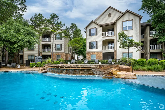 Inviting apartment community with stylish architecture and a refreshing swimming pool surrounded by lush greenery.