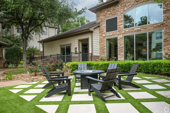 Charming outdoor space with modern patio furniture set amidst lush greenery and stylish stone architecture.