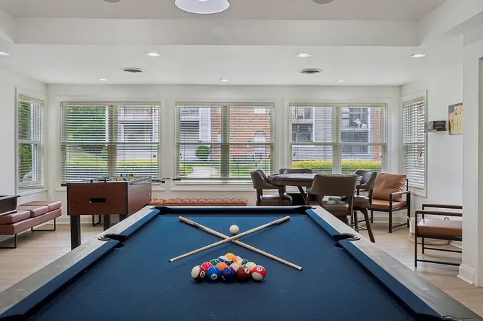 Bright and inviting recreation room with a pool table, foosball table, and cozy seating area, perfect for entertainment and relaxation.