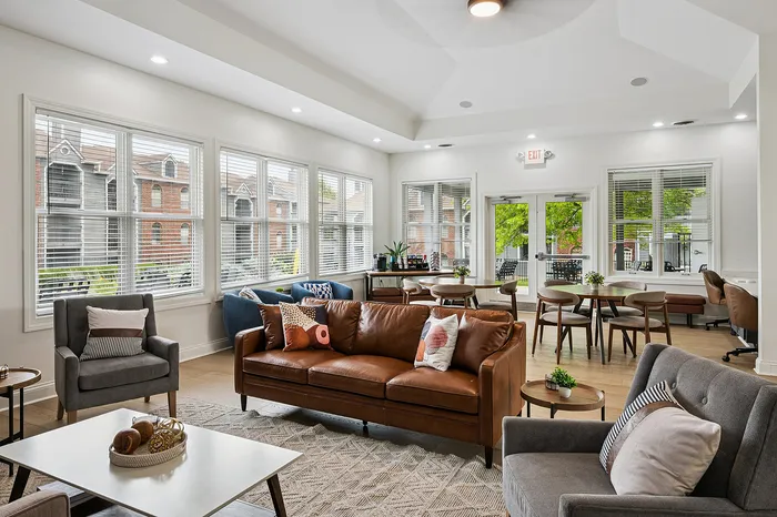 Bright and inviting communal lounge featuring stylish leather sofas, chic armchairs, and large windows with scenic views.