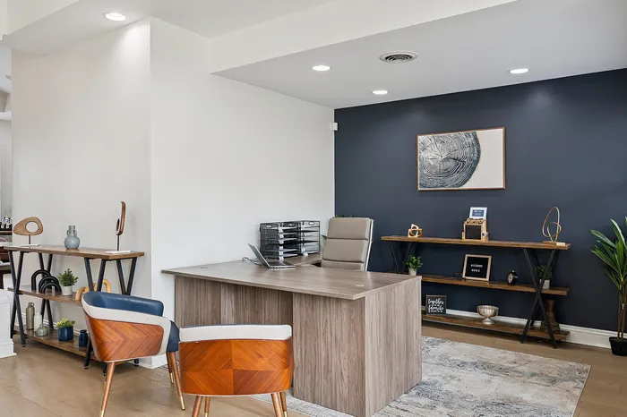 Modern home office featuring a sleek wooden desk, elegant d&eacute;cor, and a stylish accent wall with contemporary artwork.