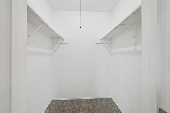 Spacious walk-in closet with ample shelving and hanging space, perfect for organized living.