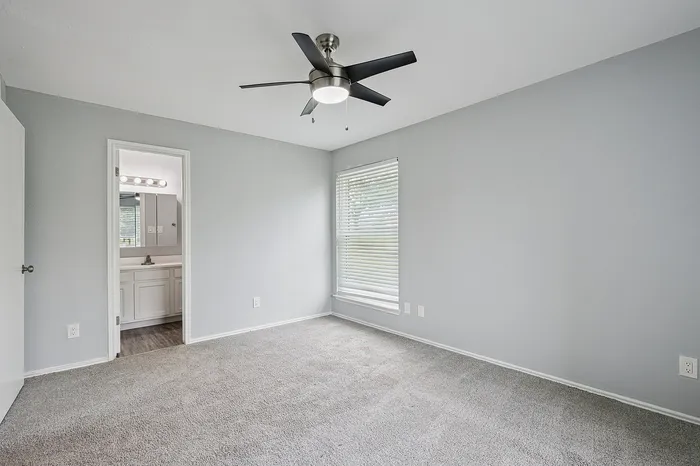 Bright and airy bedroom with plush carpeting and modern ceiling fan, featuring an en-suite bathroom for added convenience.