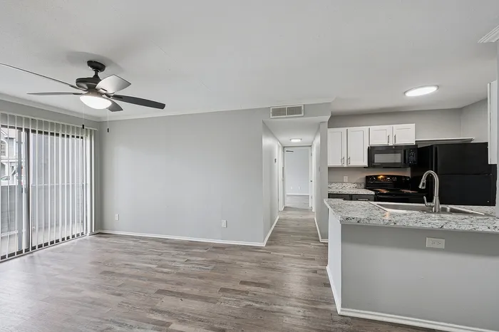 Modern open-concept living space with sleek hardwood floors, granite countertops, and abundant natural light from large sliding doors.