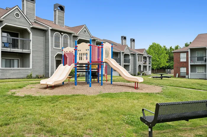 Charming apartment complex with a vibrant playground and lush green spaces, perfect for family living.