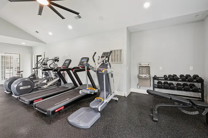 Modern fitness center with state-of-the-art treadmills, exercise bike, elliptical machine, and free weights for a complete workout experience.