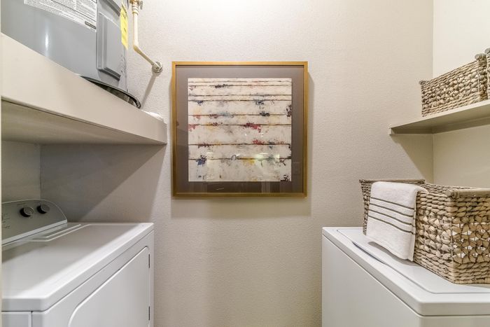 Charming laundry room with modern appliances, stylish shelving, and elegant wall art.