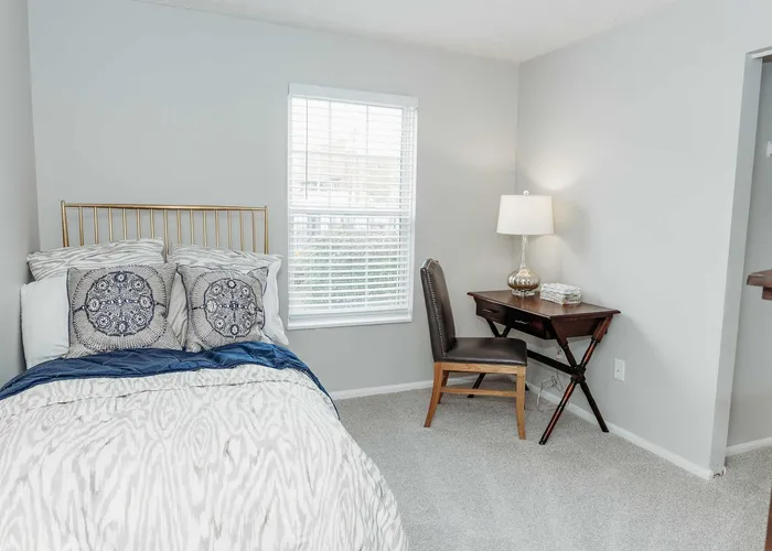 Charming bedroom with a cozy bed, elegant desk setup, and soft natural light through the window, perfect for relaxation and productivity.