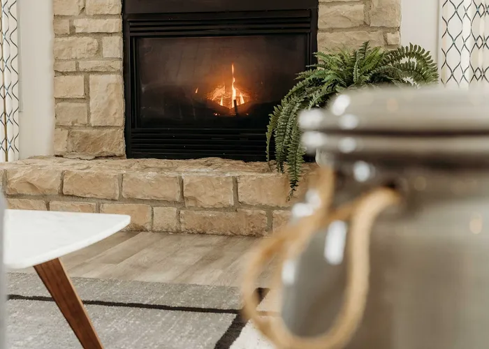 Cozy living room with a charming stone fireplace, warm lighting, and stylish decor accents.