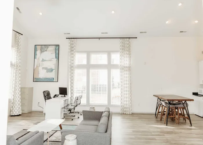 Bright and airy open-concept living space with modern furnishings, showcasing a stylish office area and chic dining setup.