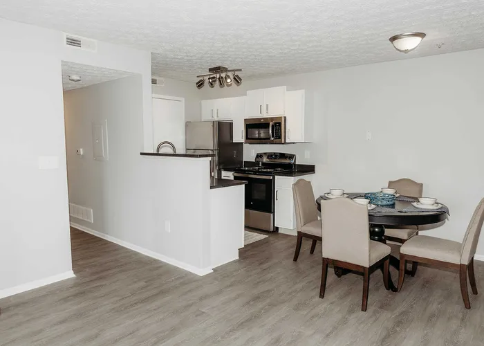 Inviting open-concept kitchen and dining area with sleek stainless steel appliances and elegant furnishings, ideal for modern living.