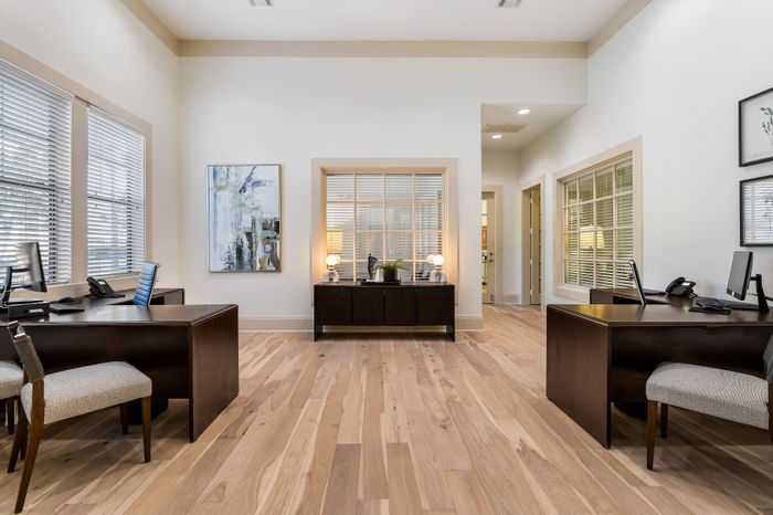 Elegant office space with warm wood flooring, modern desks, and ambient lighting offering a professional and inviting environment.
