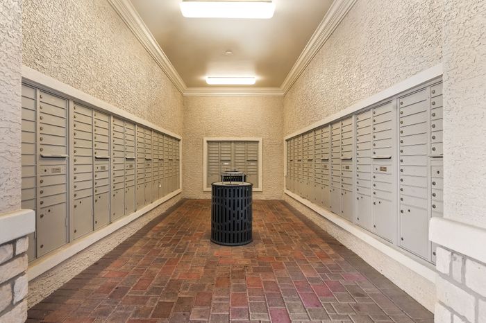 Inviting apartment mailroom featuring sleek individual mailboxes and stylish brick flooring.