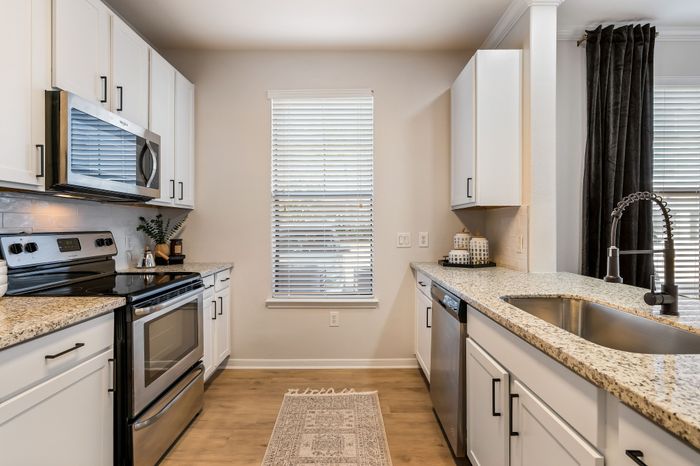 Chic modern kitchen with sleek stainless steel appliances, elegant cabinetry, and granite countertops accentuated by natural light.
