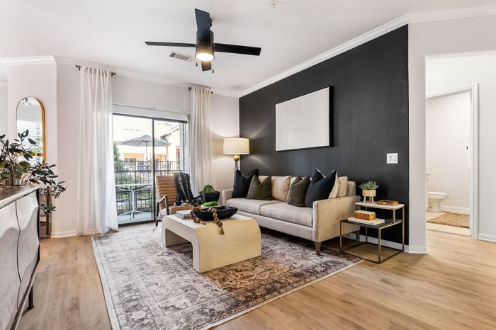 Sophisticated living room with elegant decor, featuring a plush sofa, chic coffee table, and access to a sunny balcony, perfect for stylish urban living.