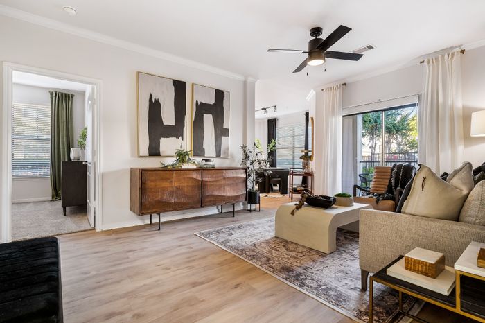 Chic open-plan living room with modern decor, elegant wooden furniture, and floor-to-ceiling windows for abundant natural light.